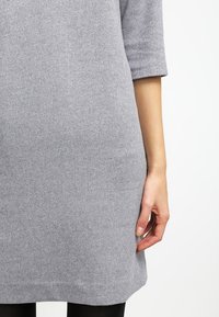 Grå ullklänning med trekvartslång ärm, smal passform, knälång längd, mjuk textur och en enkel design utan synliga mönster.