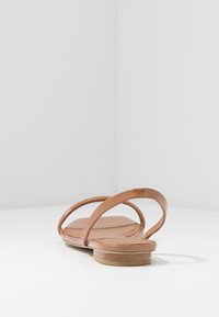 Ruske patentna usnjena sanda z ravnim podplatom, ki ima dve ukrivljeni naramnici in gladko teksturo. Minimalističen dizajn brez dodatnih detajlov.