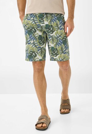 Shorts pour hommes avec imprimé feuilles vert et bleu ; tissu léger ; longueur genoux ; associés à des sandales à glissière marron.
