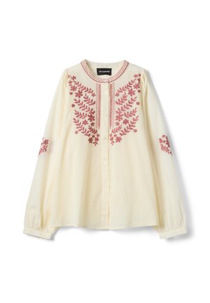 Blusa crema de manga larga con escote redondo, cierre de botones y bordado floral rojo en el pecho y las mangas.