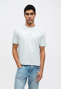 Světle modré tričko s krátkými rukávy z jemné bavlny, s kulatým výstřihem a jemným logem "BOSS" na hrudi.