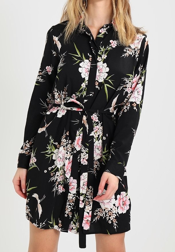 Svart långärmad klänning med rosa och vit blommig och fågeltryck, knäppt framtill och med ett matchande bälte av samma tyg knytet i midjan.