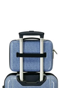 Valigia rigida blu con manico retrattile e piccola valigia abbinata fissata sopra con una cinghia nera.