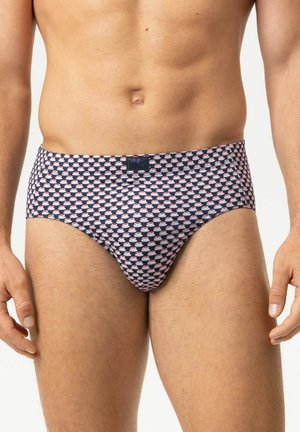 Mannelijke torso met donkere slips met patroon en kleine witte en roze kopjes op een effen lichte achtergrond.