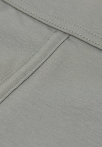 Tela gris con una textura suave, que presenta líneas y costuras sutiles. El tejido parece ligero y flexible, con un color uniforme.