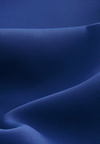 Blue textured fabric with a ribbed pattern, showing soft folds and smooth surface, conveying a lightweight and flexible material.