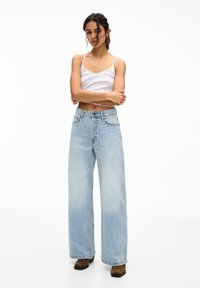 Helle blaue hochtaillierte weit geschnittene Jeans aus Denim mit einer leicht verblassten Textur, ausgestattet mit Vordertaschen und einem Knopfverschluss.