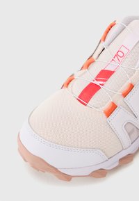 Adidași din plasă ușoară în crem cu accente portocalii. Prezintă o talpă texturată, un sistem de șireturi flexibil și o limbă căptușită pentru confort.