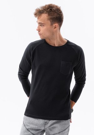 Schwarzes Langarmshirt aus strukturierter Stoff mit rundem Halsausschnitt. Mit Raglanärmeln und einer kleinen Brusttasche.