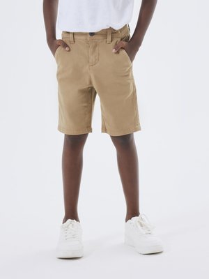 Shorts di cotone beige con design a taglio dritto, tasche laterali e chiusura con bottone, abbinati a sneakers bianche. Stile semplice e funzionale.