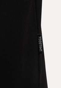 Camiseta de tela negra con una textura sutil y una etiqueta de logo en el costado. El diseño presenta un corte sencillo con mangas cortas.