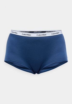 Niebieskie bawełniane figi hipster z białym paskiem w talii, na którym znajduje się czarny napis "Calvin Klein". Gładka struktura i dopasowany krój.