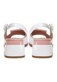Sandales en cuir verni blanc avec un talon bloc rose accentué, design à dos ouvert et sangle réglable avec boucle ronde.
