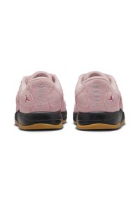 Des baskets en suède rose avec une semelle en caoutchouc noir, présentant des accents rouges et un talon texturé. Les détails notables incluent des coutures horizontales à l'arrière.