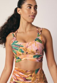 Farverig tank top med et bladmønster i grøn, pink og orange, med tynde justerbare stropper og et cropped design.