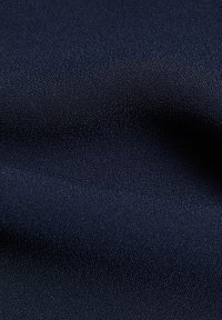 Tissu bleu marine foncé avec un tissage fin légèrement texturé et des plis doux créant des ombres et des lumières subtiles.
