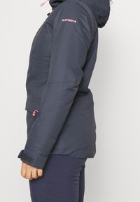 Granatowa wodoodporna kurtka z kapturem i różowymi akcentami, z zamkiem błyskawicznym kieszeni i rzepami przy mankietach; teksturowana tkanina i prosty design.