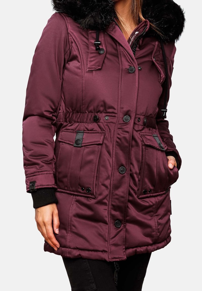 Parka bordeaux avec capuche en fausse fourrure, taille élastique, multiples poches et fermetures à boutons. Tissu texturé avec sections matelassées.