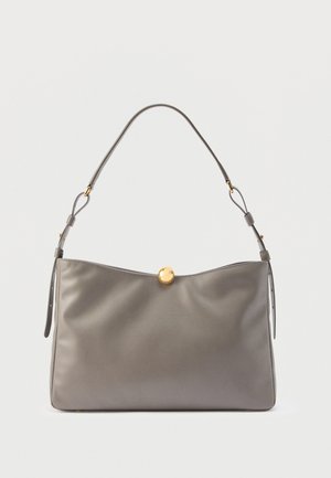 Bolso de cuero gris con correa ajustable y cierre circular dorado en la parte superior central sobre un fondo blanco.