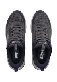 Baskets de sport en maille grises avec un design à enfiler, présentant un dessus texturé, des semelles rembourrées et une petite languette pour un enfilage facile.