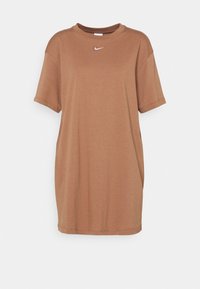 Brązowa bawełniana sukienka w kształcie T-shirtu z okrągłym dekoltem, krótkimi rękawami i małym białym logo Nike na piersi. Luźny krój.