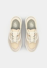 Beige sneakers med teksturert mesh og suedepaneler. Har hvite snøringer og en polstret såle. Logoen vises på innersålen.
