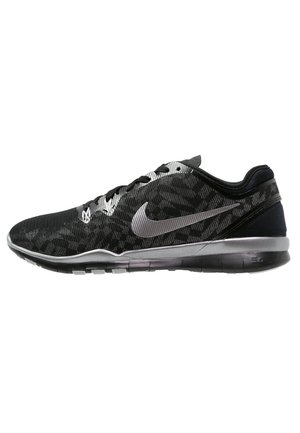 Chaussure de course Nike basse noire et grise avec fermeture à lacets et logo Nike Swoosh argenté sur le côté.