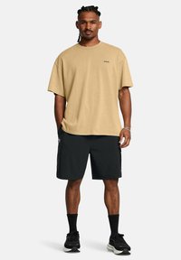 Beige oversized t-shirt med en liten logotyp, i kombination med svarta cargoshorts. Funktioner inkluderar korta ärmar och en avslappnad passform.
