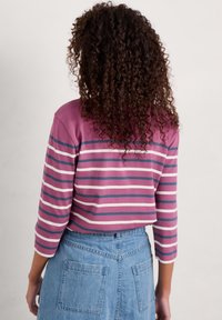 Krótki top z krótkim rękawem w różowo-niebieskie paski, wykonany z miękkiej bawełny. Posiada okrągły dekolt i luźny krój.