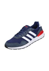 Zapatilla deportiva azul marino con rayas blancas, materiales de ante y malla, detalles en rojo, puntera redondeada y suela de goma blanca y negra.