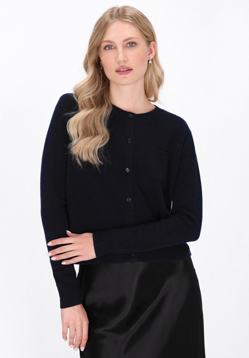 Marine gebreide cardigan met lange mouwen, ronde halslijn, vijf knopen, geribde manchetten en een klein zakje op de linkerborst.