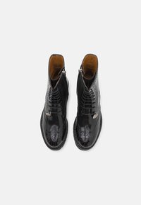 Bottines en cuir noir avec un design à lacets, des détails type wingtip et une fermeture éclair sur le côté. Tige texturée avec une finition lisse.