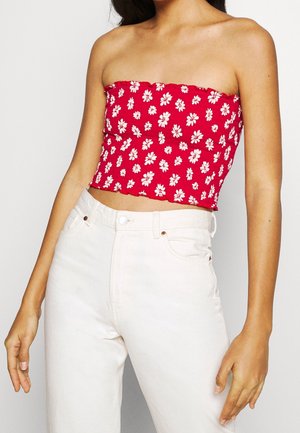 Rode bloemen crop top met witte madeliefjes, met een strapless ontwerp en gegatherde textuur; gedragen met hoge taille witte jeans.