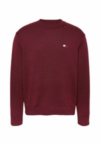 Suéter de punto burdeos con cuello redondo, puños y dobladillo acanalados. Presenta un pequeño logo bordado en el pecho.