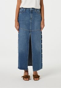 Denim maxi rok met een split aan de voorkant, lichtblauwe wassing, zilveren hartknopen aan de zijkant en een rechte pasvorm. Draag het met dierenprint slides.