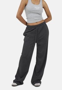 Grijze geribbelde tanktop met de tekst "NEW YORK" en zwarte comfortabele sweatpants met drawstring tailleband, gemaakt van een zachte, gestructureerde stof.