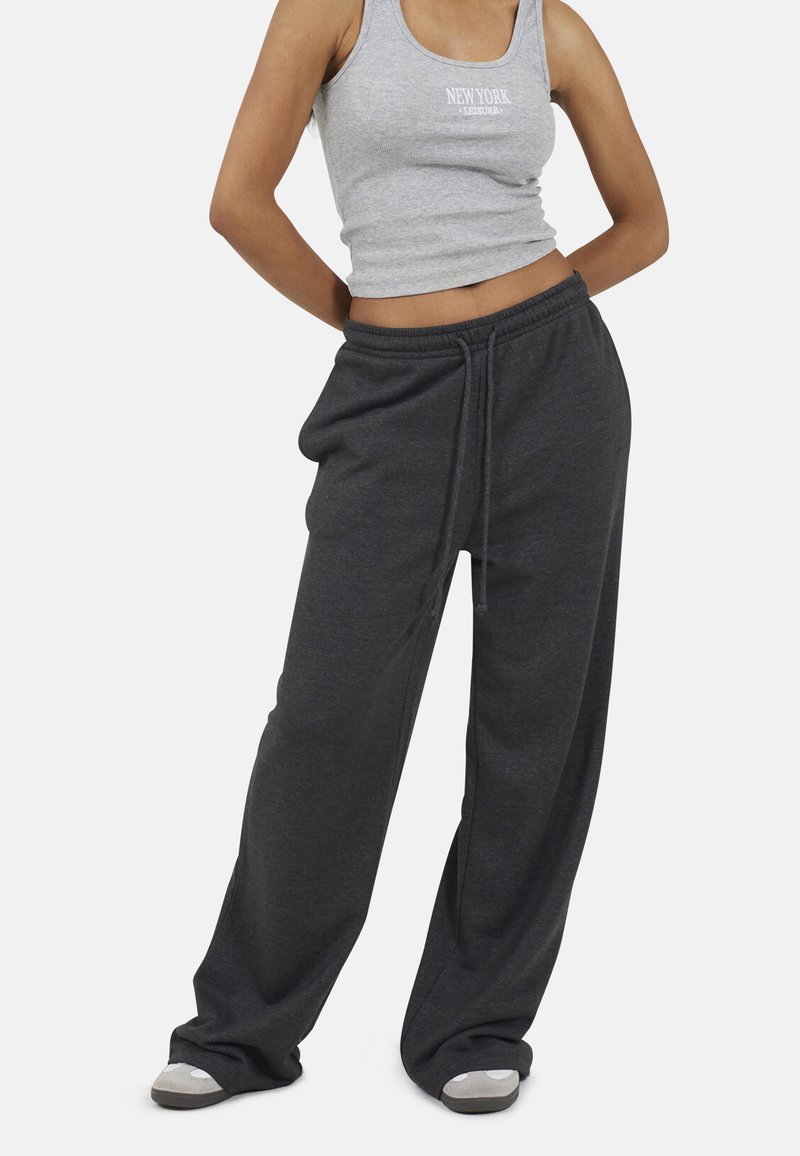 Grijze geribbelde tanktop met de tekst "NEW YORK" en zwarte comfortabele sweatpants met drawstring tailleband, gemaakt van een zachte, gestructureerde stof.