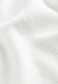 Tissu blanc texturé avec un tissage fin et doux ; surface lisse avec des variations subtiles de teinte ; tombe doucement en plis légers.