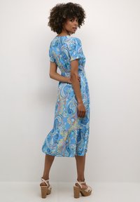 Sininen paisley-kuvioinen mekko, jossa on lyhyet puffihihat, istuva vyötärö ja levenevä helma. Materiaali vaikuttaa kevyeltä ja sileältä.
