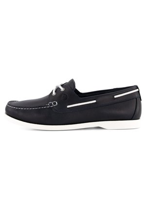 Marine leren bootsschoen met een witte rubberen zool. Voorzien van witte veters, stiksels en een decoratieve zijkantstrip. Klassiek instapmodel.