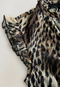 Tops s uzorkom leoparda, s kratkim volanima, izrađen od lagane tkanine s glatkom teksturom. Boje uključuju bež, smeđu i crnu.