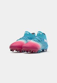 Une paire de chaussures de football bleues et roses dégradées avec un design à lacets et un logo Puma blanc sur les côtés, présentée sur fond blanc.
