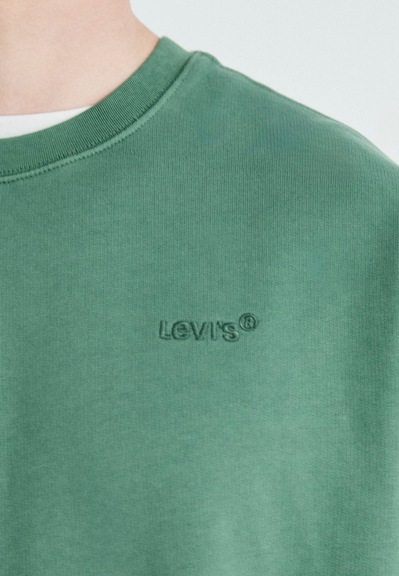 Zielony bawełniany sweatshirt z okrągłym dekoltem i haftowanym logo Levi's na piersi. Miękka tekstura i minimalistyczny design bez wzorów.