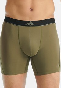 Oliivinvihreät miesten bokserit joustavasta kankaasta, joissa on musta joustava vyötärönauha harmaalla logolla, suunniteltu mukavuutta ja tukea varten.