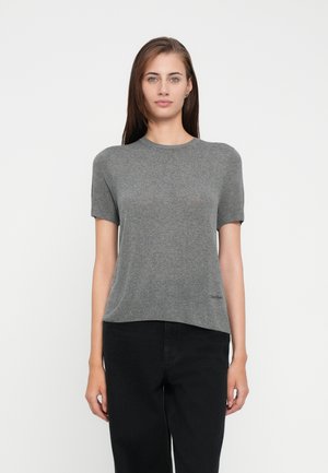 T-shirt grigio a maniche corte in un tessuto leggero. Presenta un collo rotondo e un logo discreto sull'orlo. Abbinato a pantaloni neri.