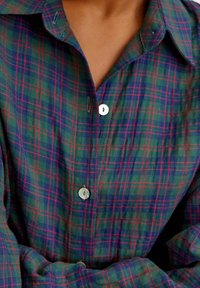 Chemise à carreaux verts avec motifs à carreaux bleus et rouges, fermeture à boutons, et col rabattable en tissu doux à fini texturé.