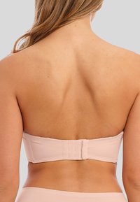 Bežová podprsenka bez ramínek s hladkým, bezešvým designem. Má zapínání na háček a očko na zadní straně a měkkou texturu látky.