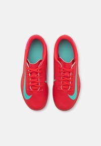 Sarkani sporta apavi ar teksturētu materiālu, ar tirkīza Nike zīmi, auklām un kontrastējošu gaiši zilu zoli.