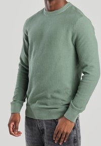 Grön texturerad sweatshirts med rund halsringning, långa ärmar och ribbade cuffs, i en åtsittande design. Avslappnad och mångsidig.