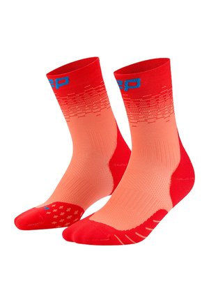 Paar rot-orangefarbener Sportsocken bis zur Mitte der Wade mit blauer Schrift near oben und strukturierten Griffmustern an Sohlen und Zehen.